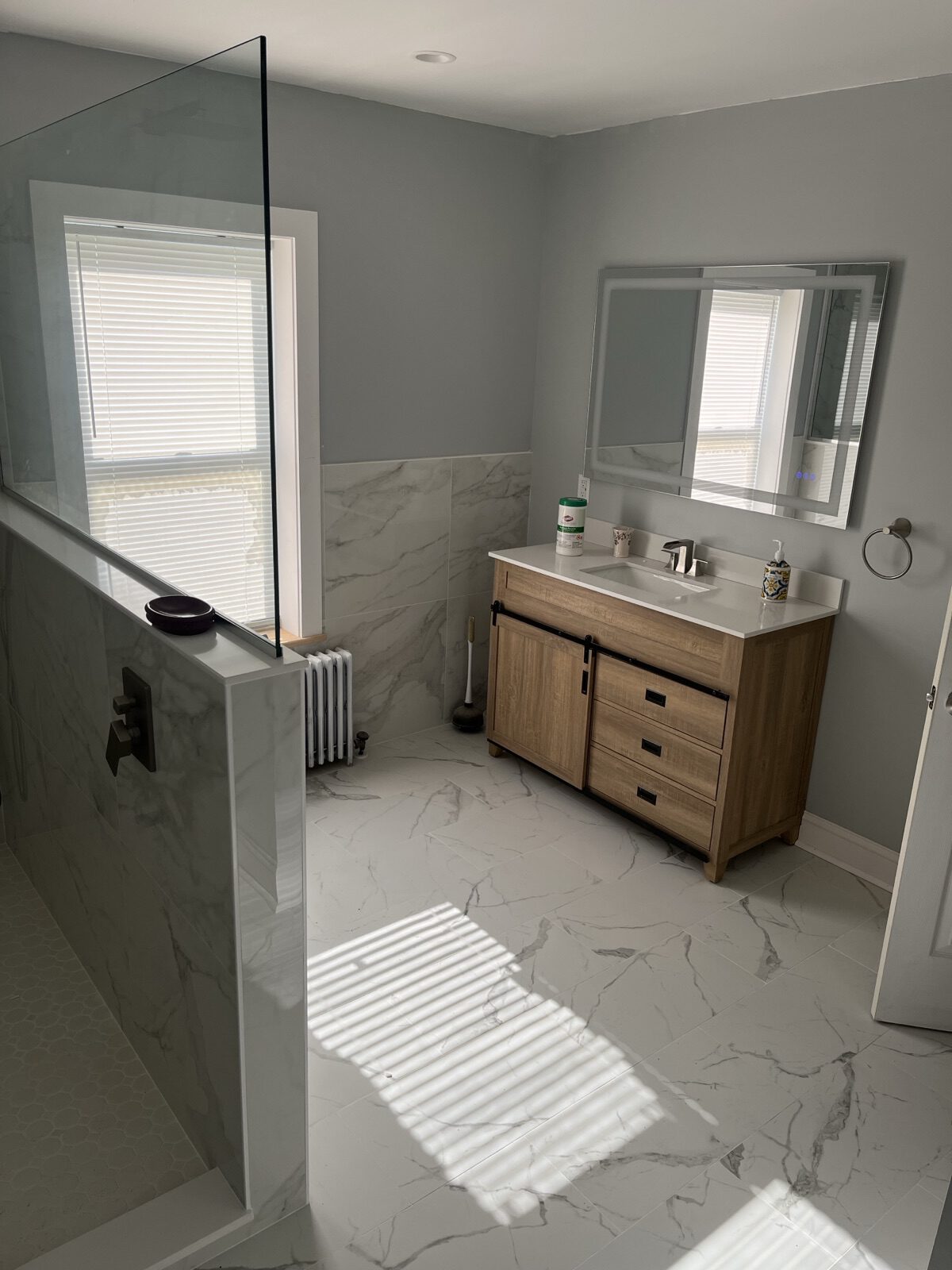 Remodeled bathroom with marble-look tile, a wood vanity, and a walk-in shower