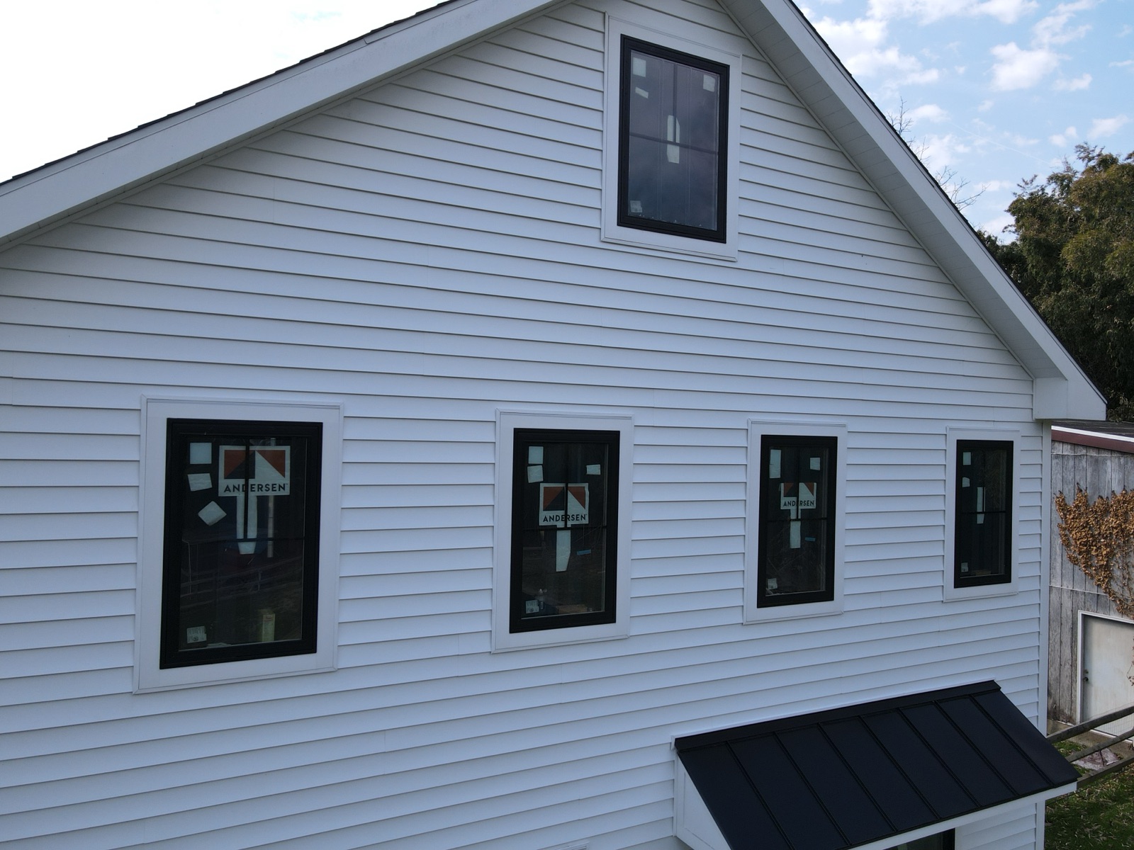 Exterior of a home with fresh white siding and new black-framed windows